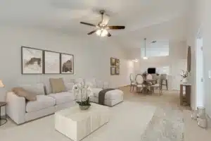 A modern living room with a beige sectional sofa, a light wood coffee table, ceiling fan, and adjacent dining area with a round table and six chairs.